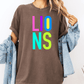 A person wearing a brown t-shirt with the word "LIONS" in colorful letters, along with a denim jacket, stands against a white background.