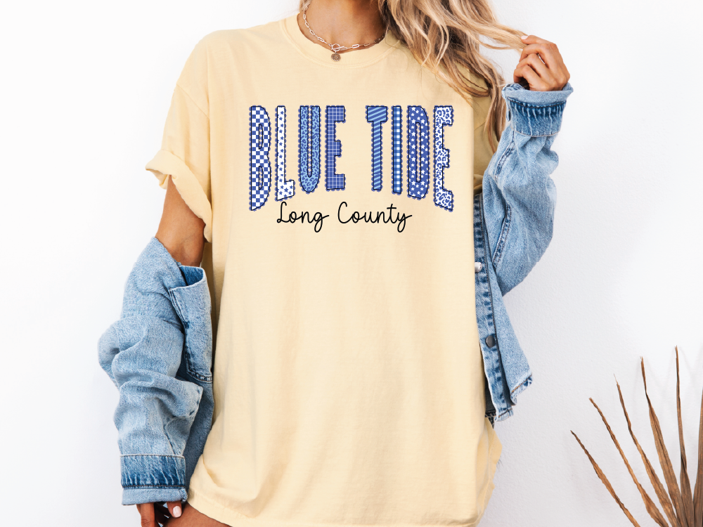 A woman wearing a yellow t-shirt with the text "BLUE TIDE Long County" printed on it, along with a denim jacket.