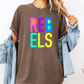A person wearing a brown t-shirt with the word "REBELS" in colorful letters, paired with a denim jacket.