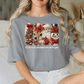 A woman wearing a gray t-shirt with a graphic design of Santa Claus, reindeer, and a snowman.