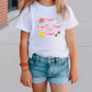 a little girl wearing a t - shirt with flowers on it