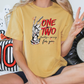 a woman sitting on a bed holding up a peace sign