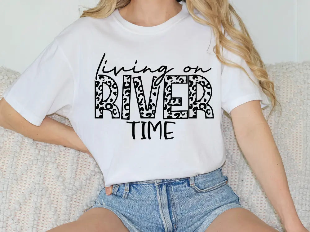 a woman sitting on a couch wearing a white shirt that says living on river time