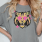 A woman wearing a gray t-shirt with a graphic design of a lion's face and stars on it.