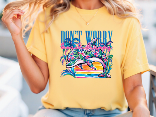 A woman wearing a yellow t-shirt with a colorful graphic of a dolphin and tropical plants printed on it.