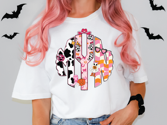 A person with pink hair wearing a white t-shirt with a colorful monogram design.