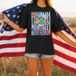 A woman stands in a field holding an American flag, wearing a black t-shirt with a graphic design featuring a duck wearing sunglasses and the word "MERICA".
