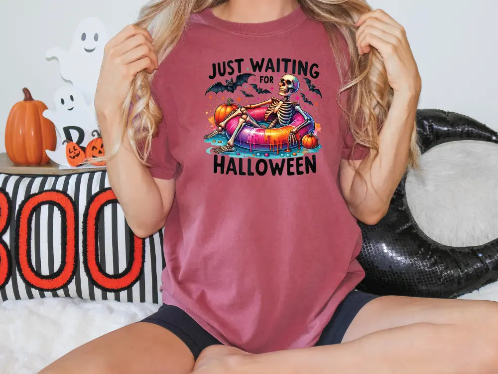 a woman sitting on a bed wearing a t - shirt that says just waiting for