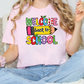 A woman wearing a pink t-shirt with a colorful graphic that says "Welcome back to school".