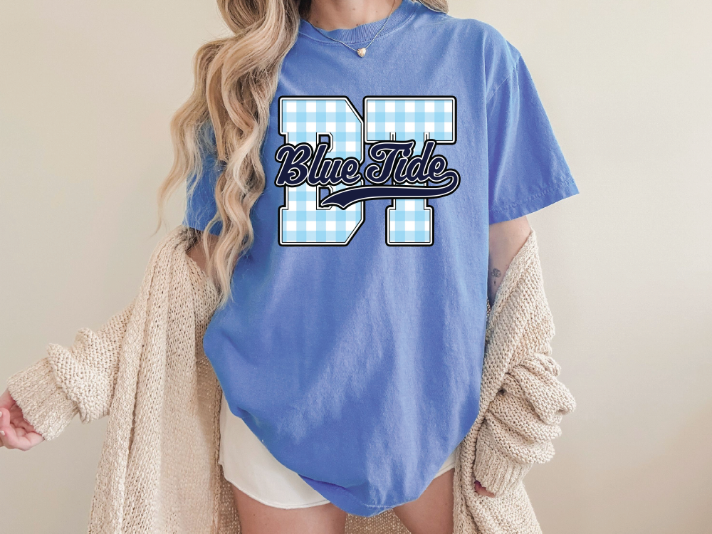 A woman wearing a blue t-shirt with the text "Blue Tide" printed on it, standing in front of a plain background.