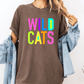 A person wearing a brown t-shirt with the text "WILD CATS" in colorful letters, along with a denim jacket, stands against a white background.