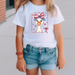 a little girl wearing a patriotic t - shirt and denim shorts