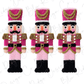 Three nutcracker figurines in a row, each wearing a pink and gold uniform with a hat and a red bow tie.