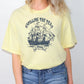 a woman wearing a yellow shirt with a sailing ship on it