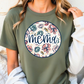 A woman wearing a green t-shirt with a floral design and the word "MEMA" printed on it.