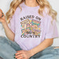 a woman sitting on the floor wearing a t - shirt that says raised on country