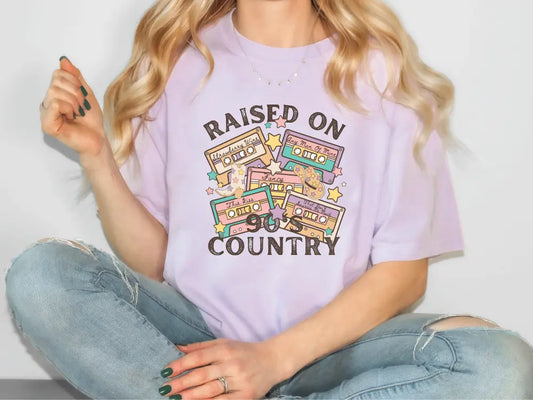 a woman sitting on the floor wearing a t - shirt that says raised on country