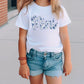 a young girl wearing a white shirt and denim shorts