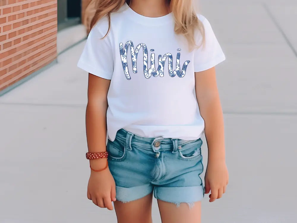 a young girl wearing a white shirt and denim shorts