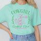 a woman wearing a green cowgirl tee shirt