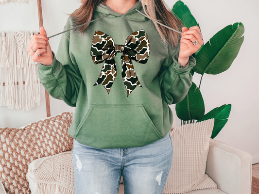 a woman wearing a green hoodie with a leopard print bow on it