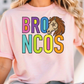 A woman wearing a pink t-shirt with the text "BRO N COS" printed on it.