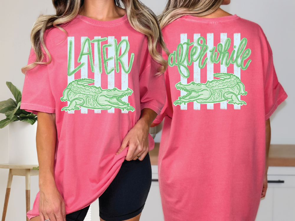 two women wearing pink t-shirts with a graphic design featuring a green alligator and the text "later after while" printed on them.