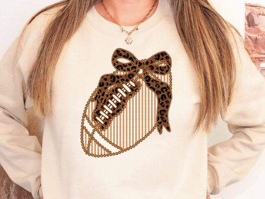 A woman wearing a white sweatshirt with a leopard print design and a football on it.