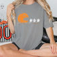 A woman wearing a gray t-shirt with a Halloween-themed graphic of a pumpkin and three ghostly figures.