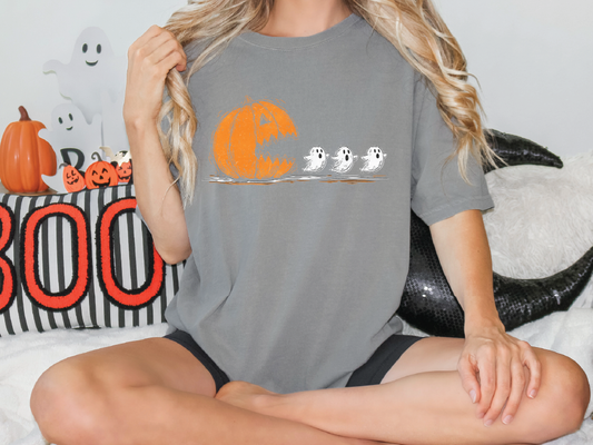 A woman wearing a gray t-shirt with a Halloween-themed graphic of a pumpkin and three ghostly figures.