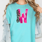 A woman wearing a turquoise t-shirt with a pink and black graphic design on it, and a denim jacket.