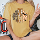 A person is sitting on a couch with a yellow t-shirt featuring a graphic design, including a leopard, a bow, and a bat.