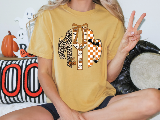 A person is sitting on a couch with a yellow t-shirt featuring a graphic design, including a leopard, a bow, and a bat.