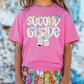 a little girl wearing a pink shirt and colorful shorts