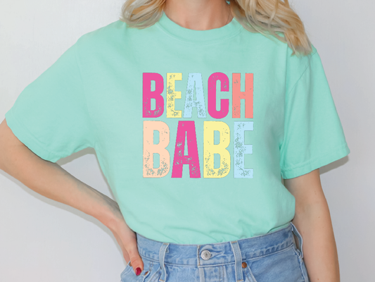 a woman wearing a green beach babe t - shirt