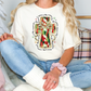 a woman sitting on a bed wearing a t - shirt with a cross on it