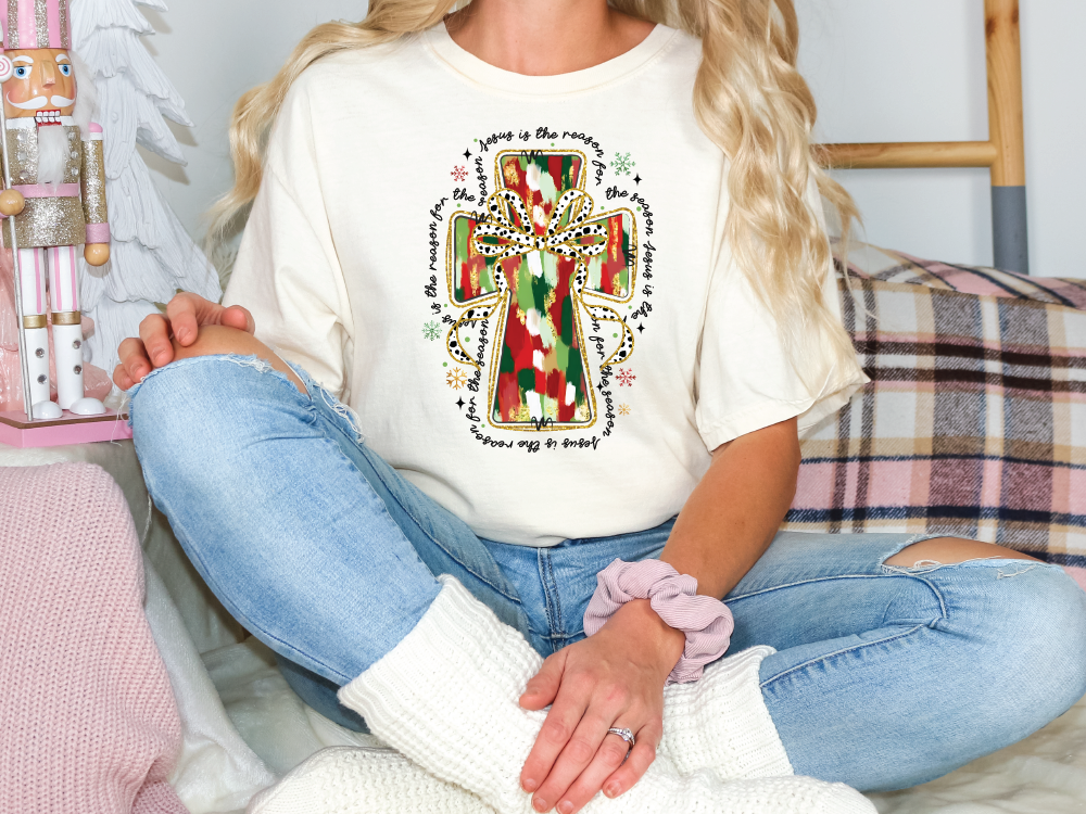 a woman sitting on a bed wearing a t - shirt with a cross on it