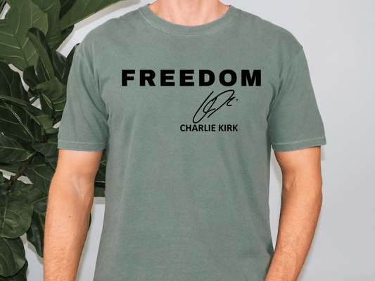 A person wearing a green t-shirt with the text "FREEDOM" and a signature below it.
