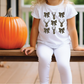 a little girl sitting on a bench next to a pumpkin