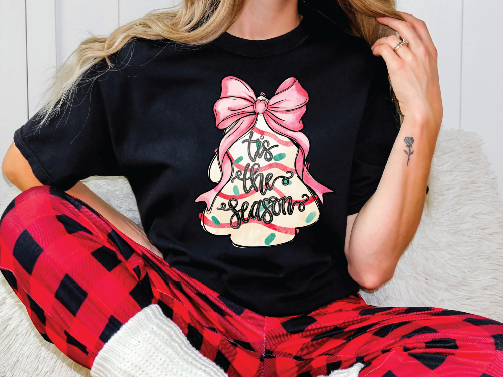 a woman sitting on a couch wearing a black t - shirt with a pink bow