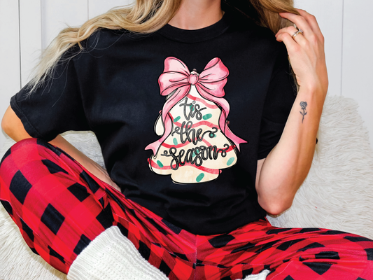 a woman sitting on a couch wearing a black t - shirt with a pink bow