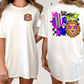 A white t-shirt with a colorful graphic design on the back, featuring a lion and various stars and shapes.