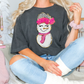 a woman sitting on a bed wearing a t - shirt with a snowman on