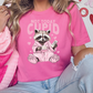 a woman wearing a pink shirt with a raccoon on it