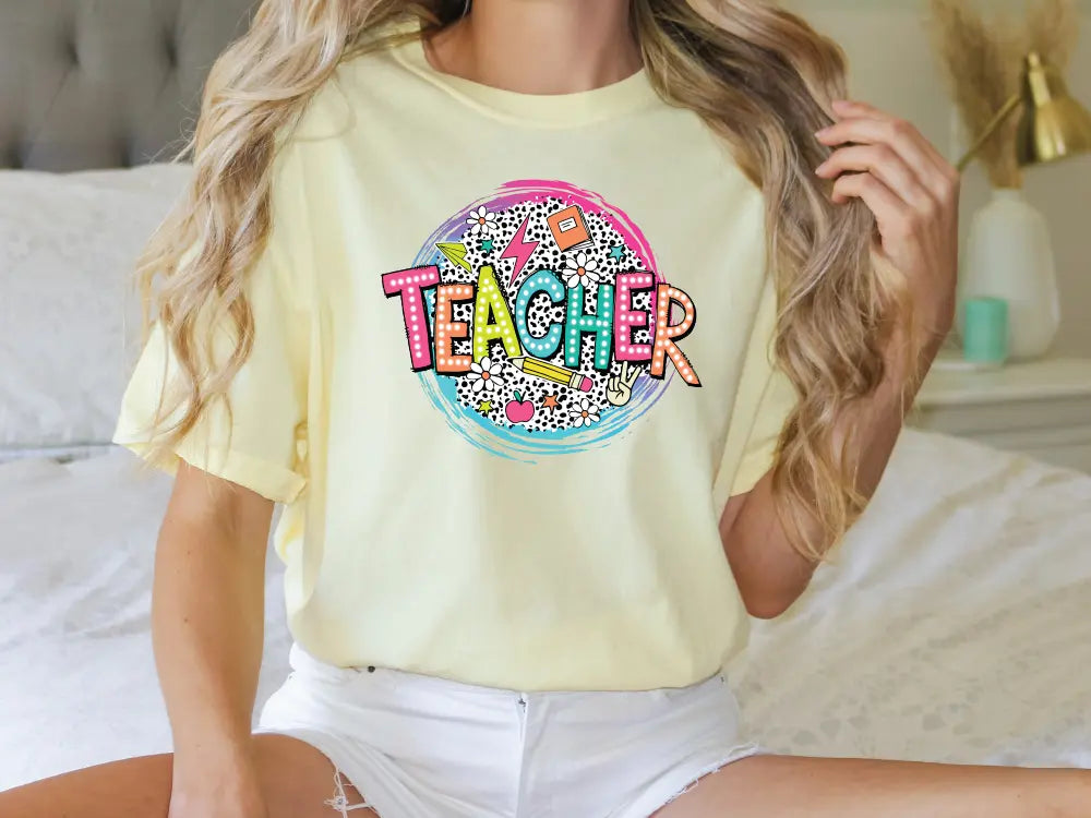 a woman sitting on a bed wearing a yellow teacher shirt