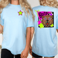 two women wearing light blue t-shirts with a graphic design on the back.