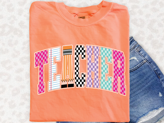 a bright orange t-shirt with the word "TEACHER" printed on it, along with colorful geometric shapes that spell out the word.