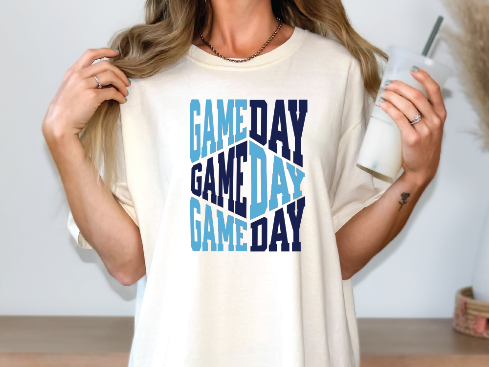 a woman is holding a cup and a game day t - shirt