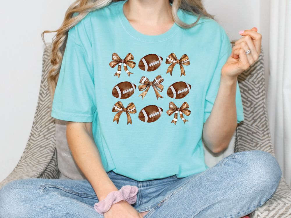 a woman sitting on a couch wearing a t - shirt with footballs on it