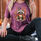 a woman sitting on the ground wearing a shirt with a raccoon on it